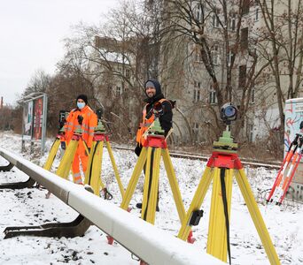 Arbeiter mit Messgeräten neben einem Gleis im Winter