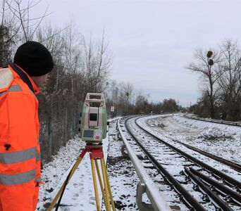 Ein Arbeiter bei Vermessungsarbeiten an einem verschneiten Gleis