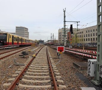 Blick auf ein Gleisfeld, links fährt eine S-Bahn, rechts ein Regionalzug.