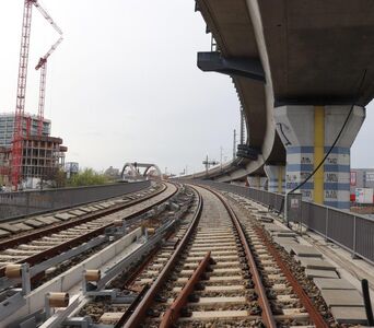 Blick auf zwei Gleise auf einer Brücke, rechts darüber eine weitere Eisenbahnbrücke.